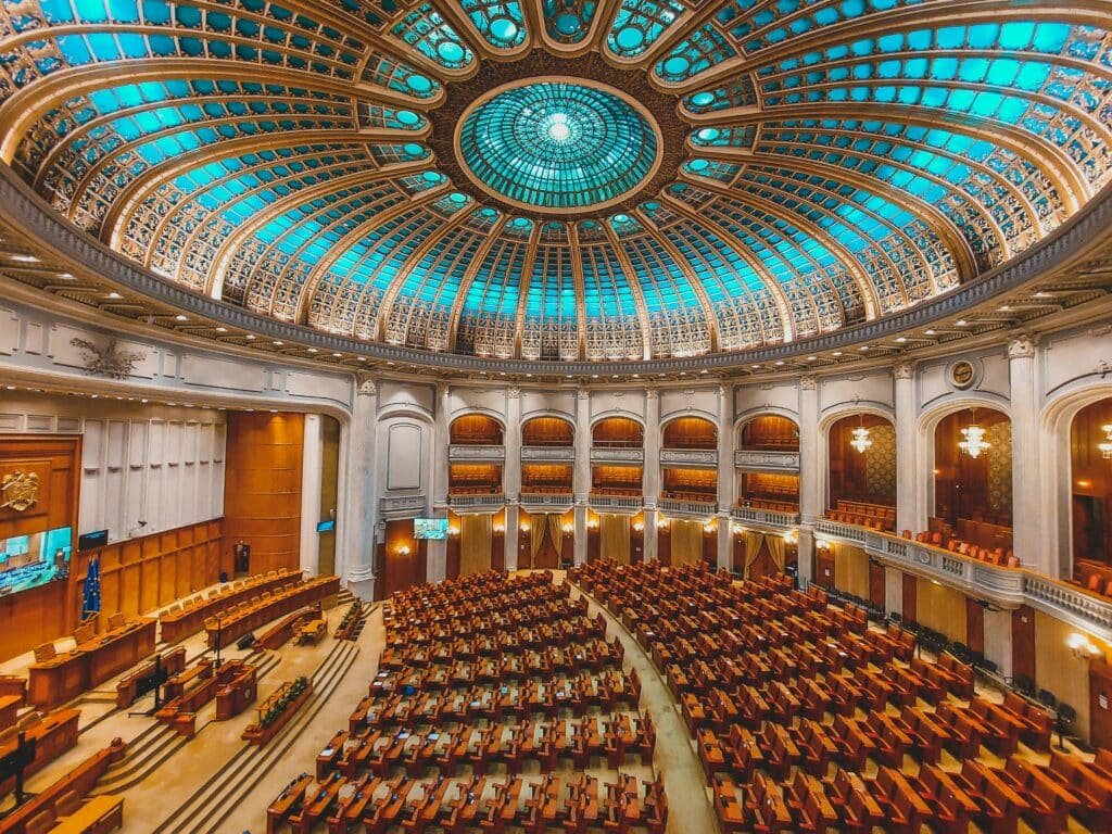 Settelix Vibrant interior of a parliament hall with a grand dome and intricate architecture.