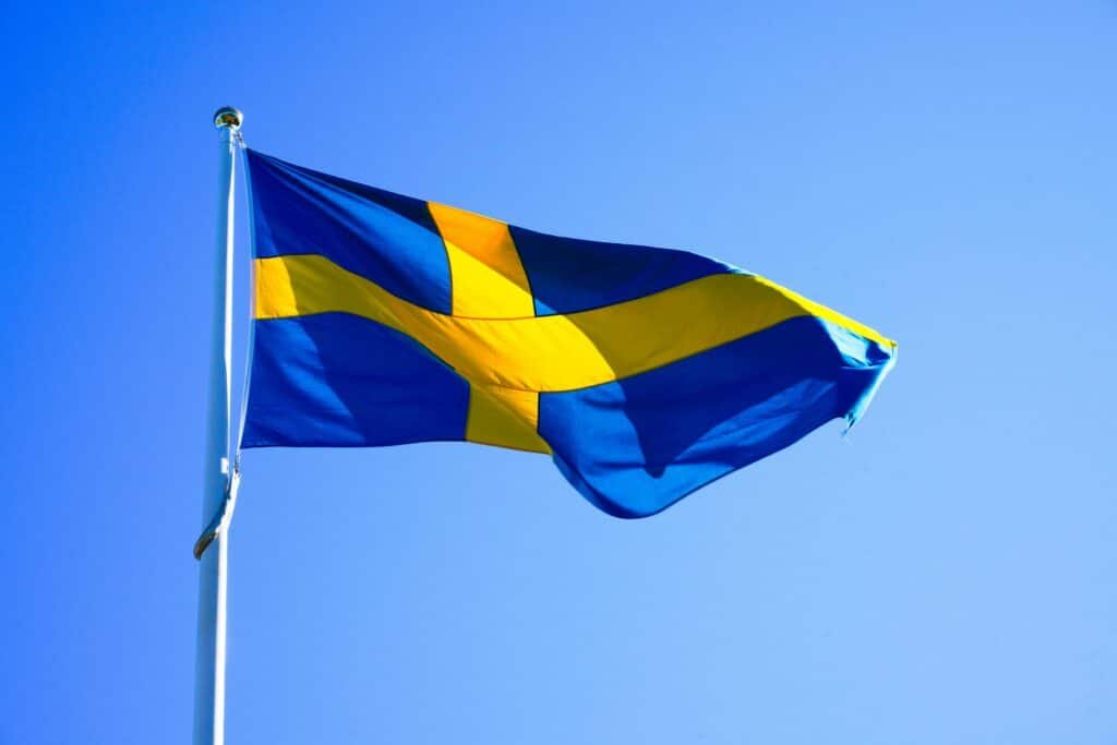 Bright Swedish flag waving on a clear day with blue sky.