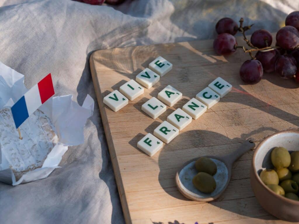 French-themed picnic setup with cheese, grapes, and 'Vive la France' spelled out in letter tiles.